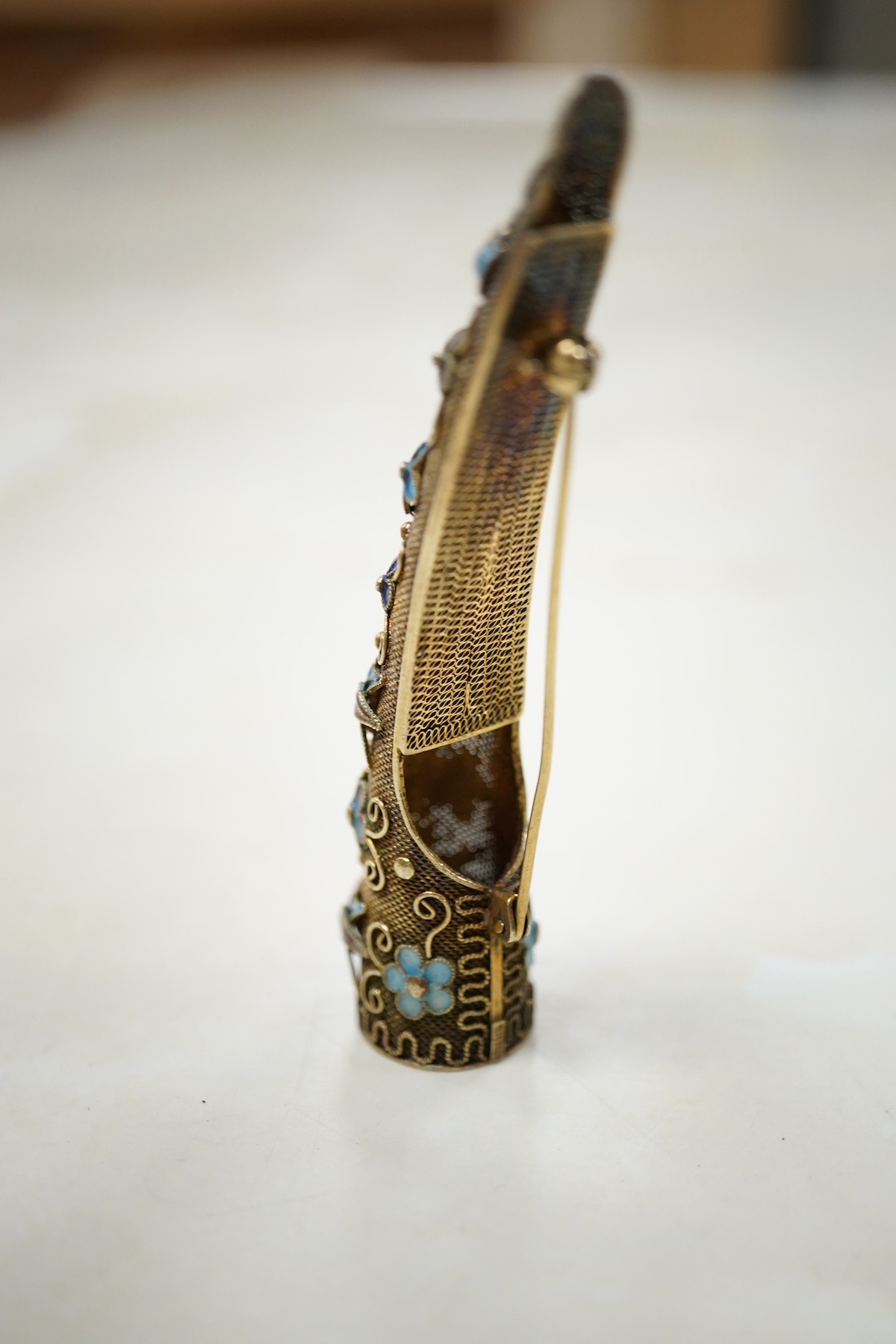 A Chinese silver gilt coral and turquoise nail guard brooch, composed of filigree, set with coral and turquoise cabochons, applied with foliate designs in blue enamel, length 8.4cm, stamped SILVER, Condition: in good con